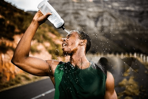 African American athlete splashing water on his face to cool down after a challenging run, emphasizing the importance of hydration after exercise.