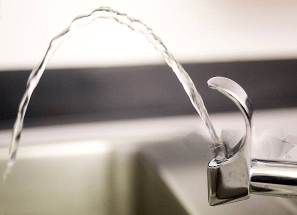 A technician assesses a sink with brown tap water in Houston, highlighting the impact of environmental factors on water quality.