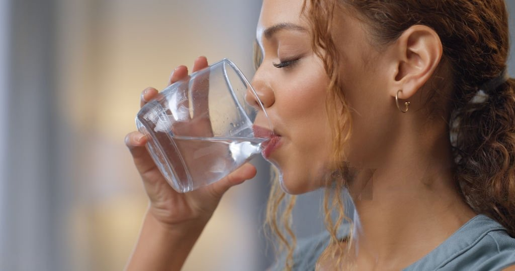 Drinking Water RO System, Close-up of a happy woman drinking a glass of water at her house, representing hydration, wellness, and a healthy lifestyle.