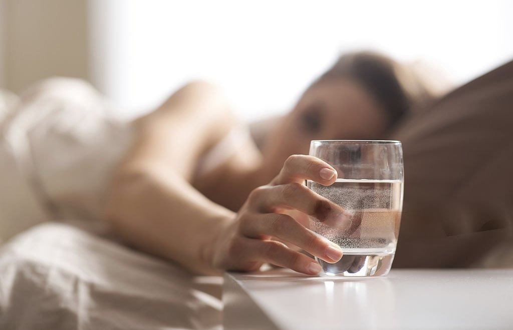 A close-up view of a woman's hand grasping a glass of water, symbolizing the importance of morning hydration. benefits of drinking water in the morning