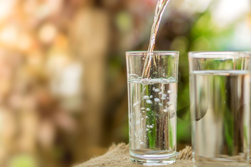 Fresh water being poured into a glass under morning sunlight, symbolizing hydration and detoxification. benefits of drinking water in the morning